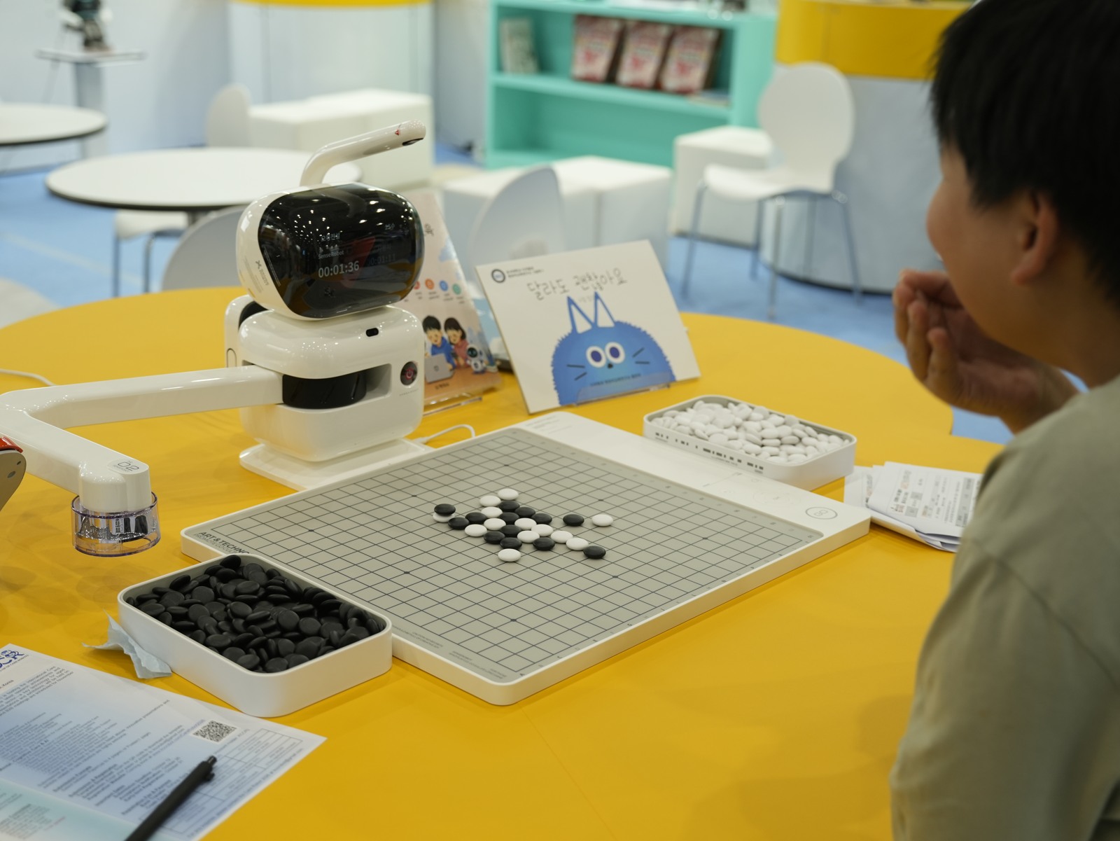 SenseRobot 用机械臂在真实棋盘上落子，旁边的观众正在看棋。